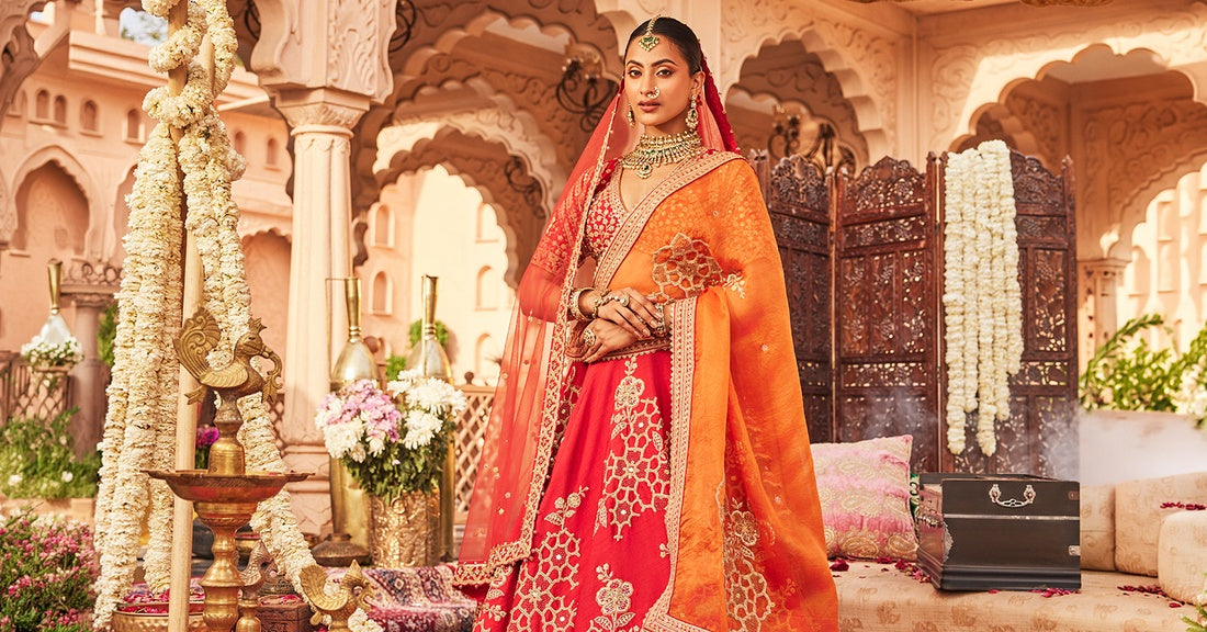 Bride in a red and orange hand-embroidered lehenga styled for a traditional Indian wedding.