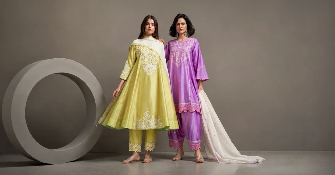 Two women wearing elegant Chanderi silk ethnic outfits in vibrant yellow and purple shades with intricate embroidery, showcasing luxury Indian traditional fashion.